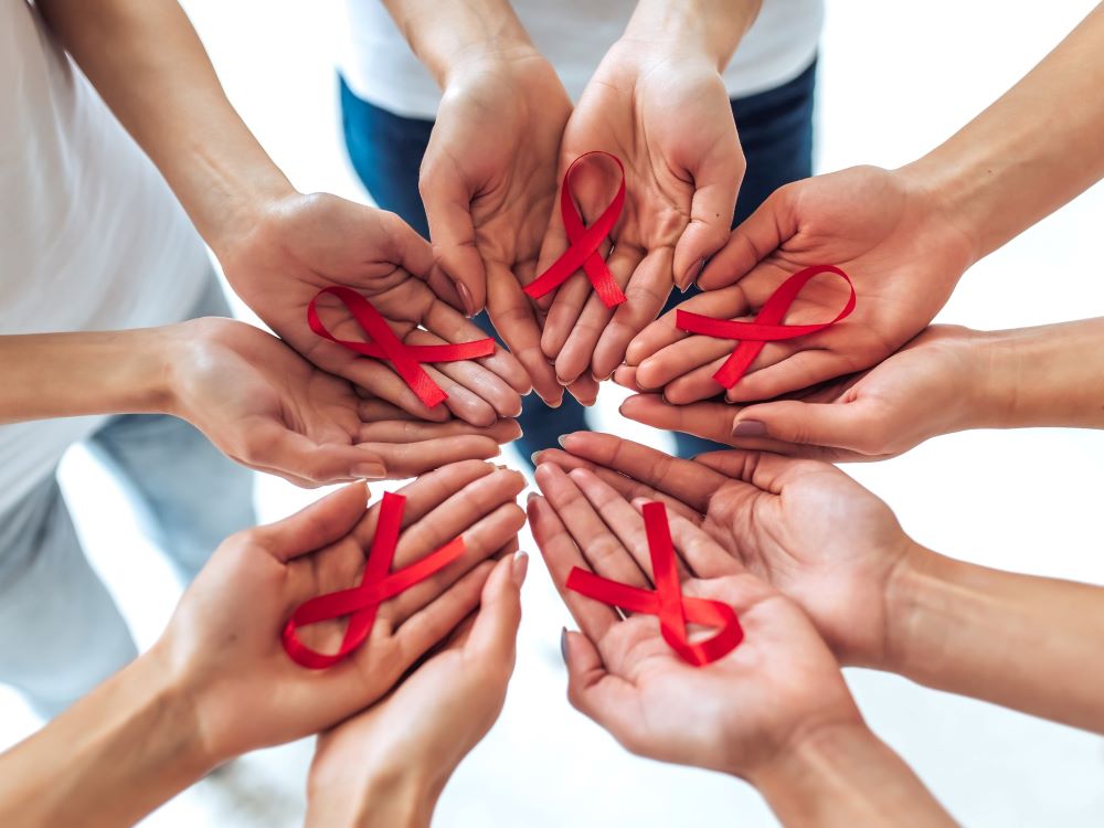 multi-racial hands holding red ribbons