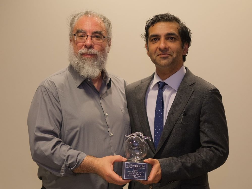 two researchers holding an award