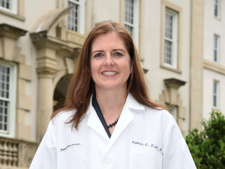 investigator wearing lab coat by building