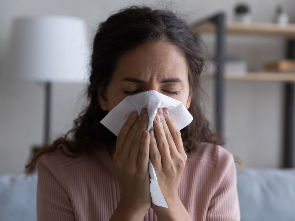 woman holding tissue over nose
