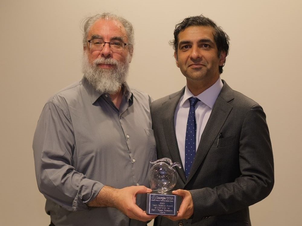 two researchers holding award